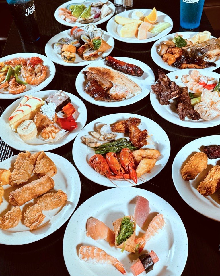 A table of plates with sushi, hibachi, seafood and fried dishes