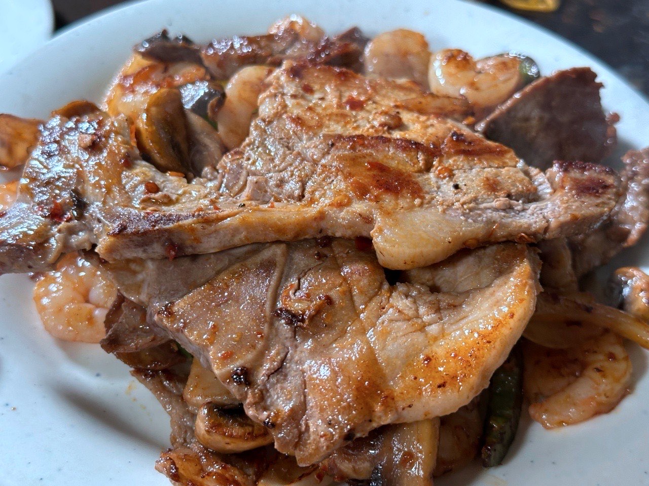 Grilled pork chops piled with shrimp and mushrooms