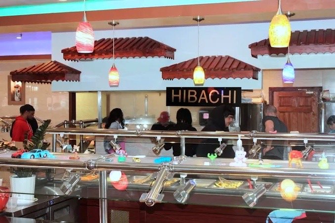 Hibachi counter with guests being served under colorful pendant lights